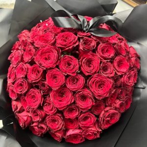 a bouquet of 100 red roses topped with a black bow