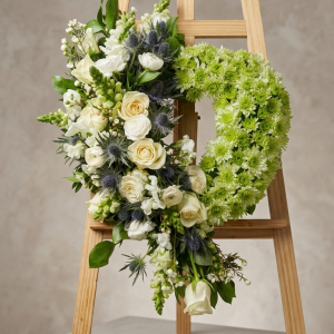 Heart shaped wreath on easel stand with mixed greens sympathy tribute